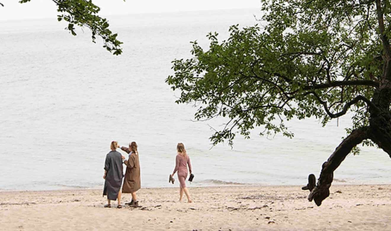 Mennesker på strand med træ i sandkanten