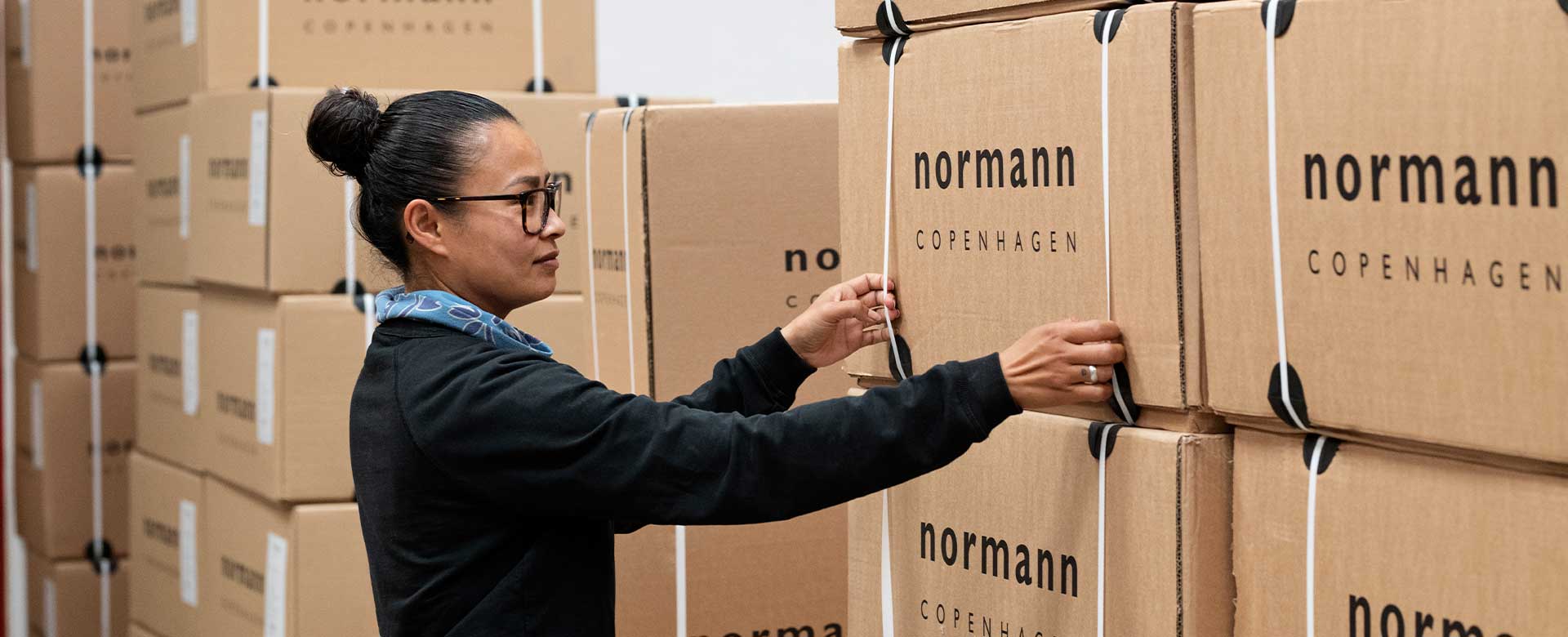 Kvinde på Normann lager flytter en papkasse