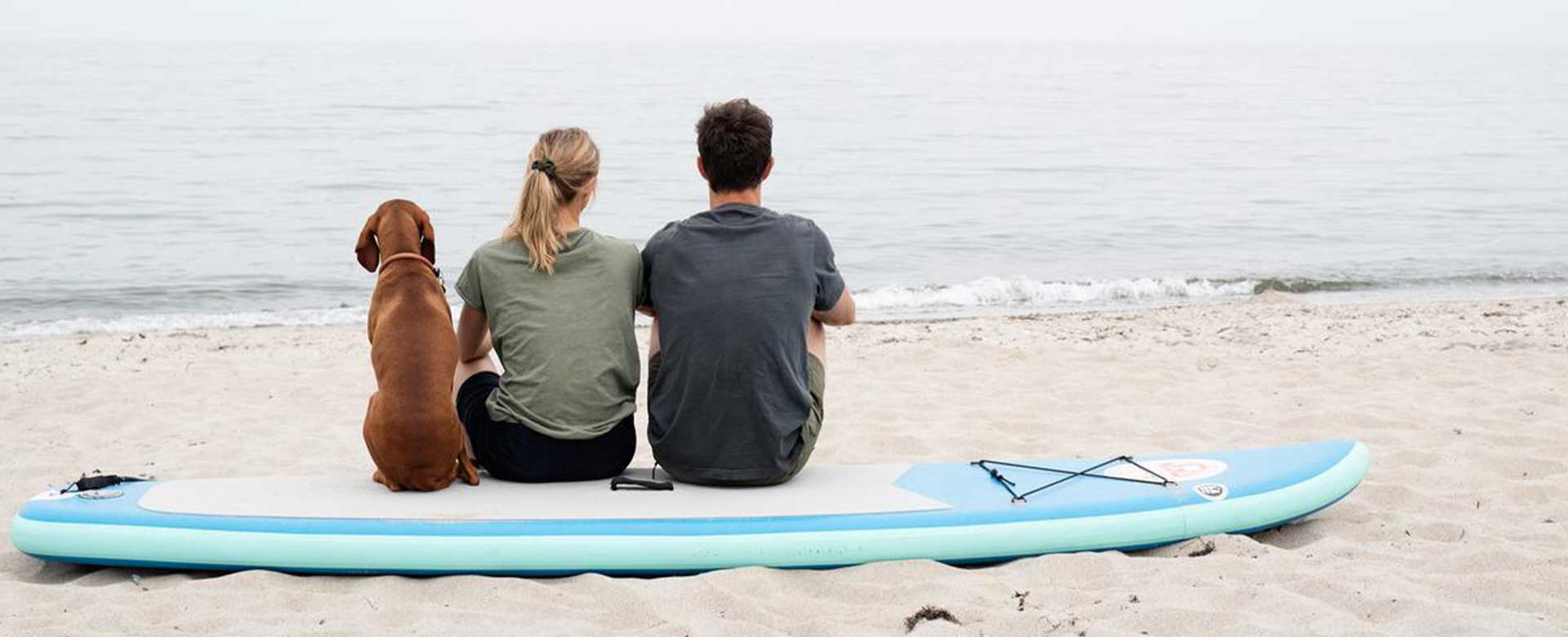 To personer og en hun på SUP board ved strand